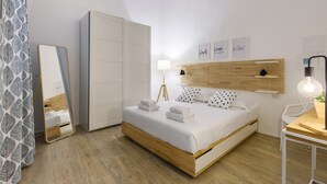 A bedroom with a bed, bedside table, lamp, and a wardrobe. - Madame Betta apartment in Florence by Mmega (Firenze)