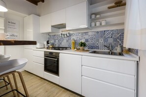 Een moderne keuken met witte kastjes, een inbouwoven, een spoelbak en een achterwand met blauwe en witte tegels.