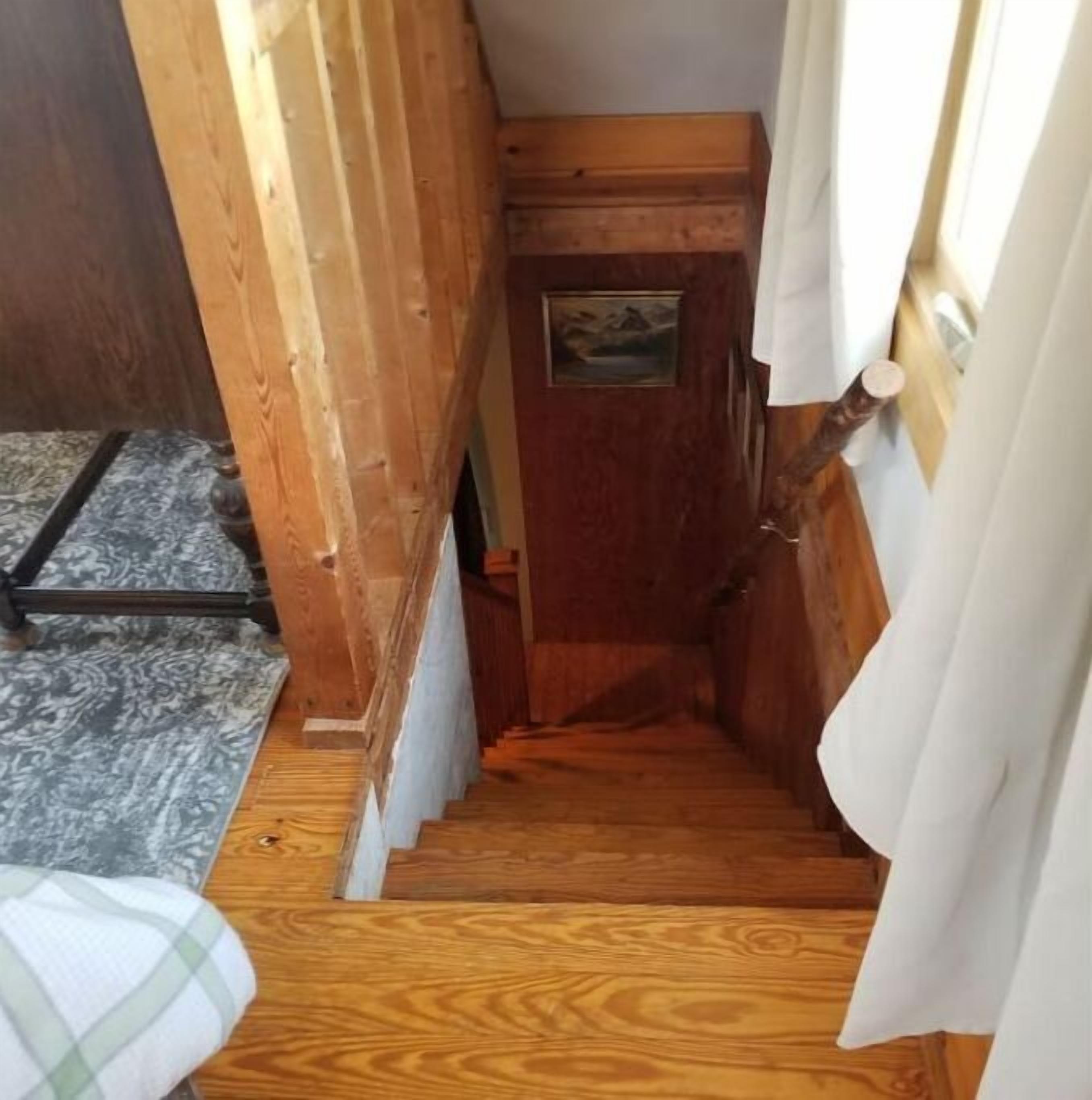 A narrow wooden staircase leading to a door with a small picture on it.