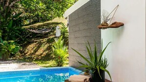 A swimming pool with a tiled edge, surrounded by lush greenery and a hammock.