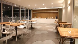 A modern dining area with hexagonal patterned flooring, wooden tables, and white chairs. - Hihome - Royale (São Bento Cabo Frio)