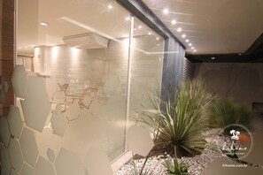 A modern interior with hexagonal glass panels, a staircase, and a small garden area with plants.