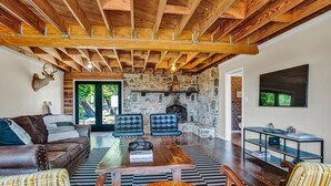 A spacious living room with a stone fireplace, leather furniture, and a high wooden ceiling. - *New| Stunning Views| Sleeps 10 (Fredericksburg)