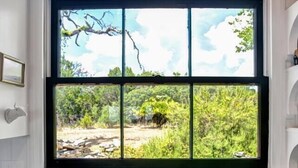 A kitchen with a double stainless steel sink, a window with a view of greenery, and a decorative wall sign above the window. - *New| Stunning Views| Sleeps 10 (Fredericksburg)