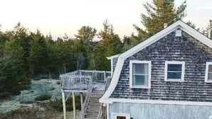 A wooden cabin with a balcony, surrounded by trees.