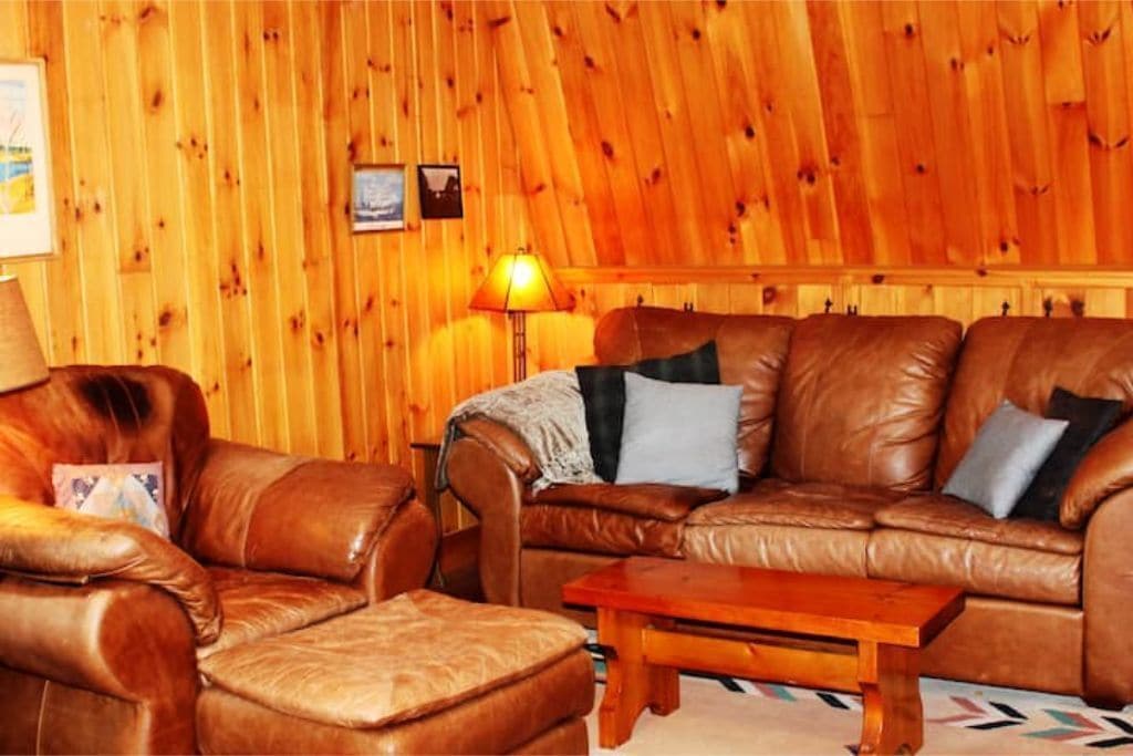 A room with a brown leather sofa, a matching armchair, and a wooden coffee table.