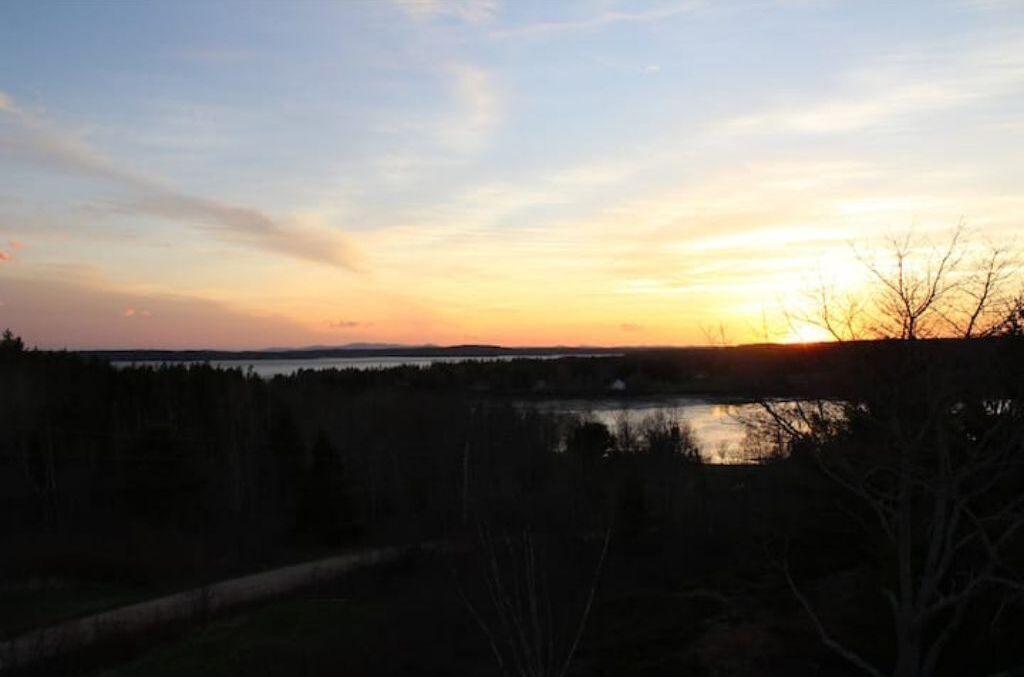 Un coucher de soleil sur un lac, avec une rive bordée d’une forêt.