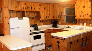 A kitchen with wooden cabinets, a white refrigerator, a stove, and a coffee maker.