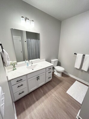 Et moderne badeværelse med et stort håndvaskarrangement, toilet og bruseforhæng.