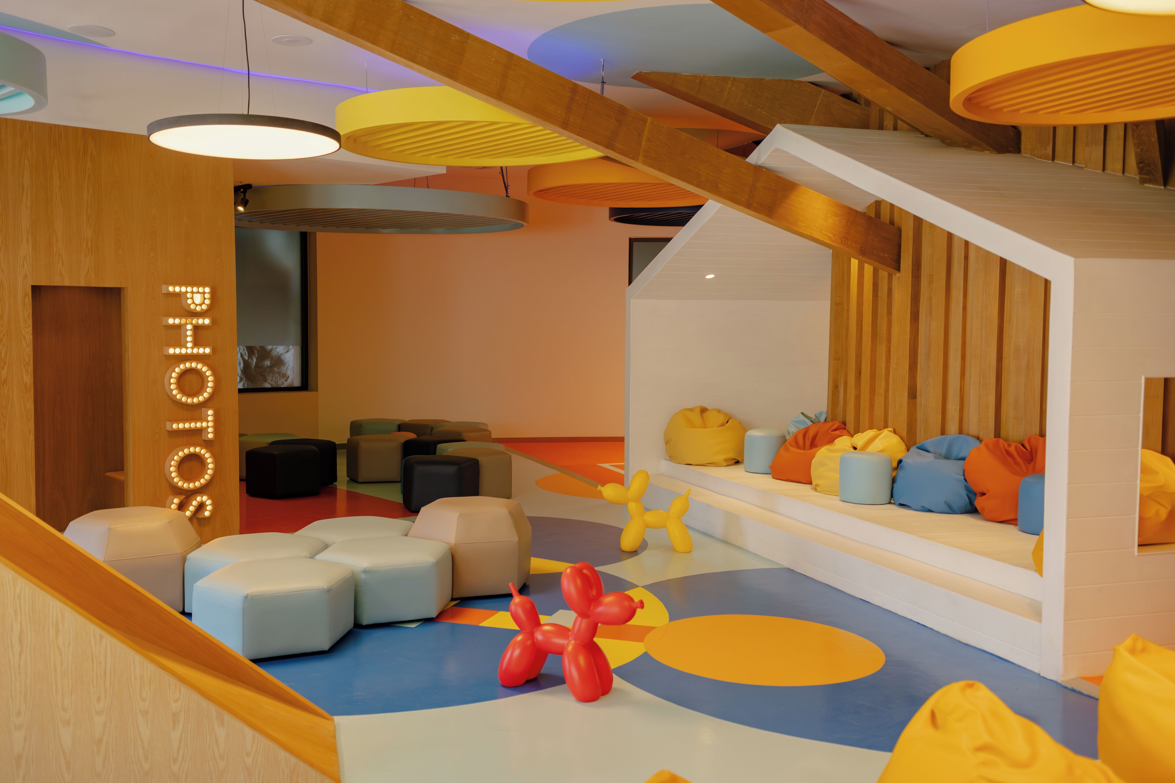 Un interior moderno con una escalera de madera, zonas de estar coloridas y un diseño alegre.