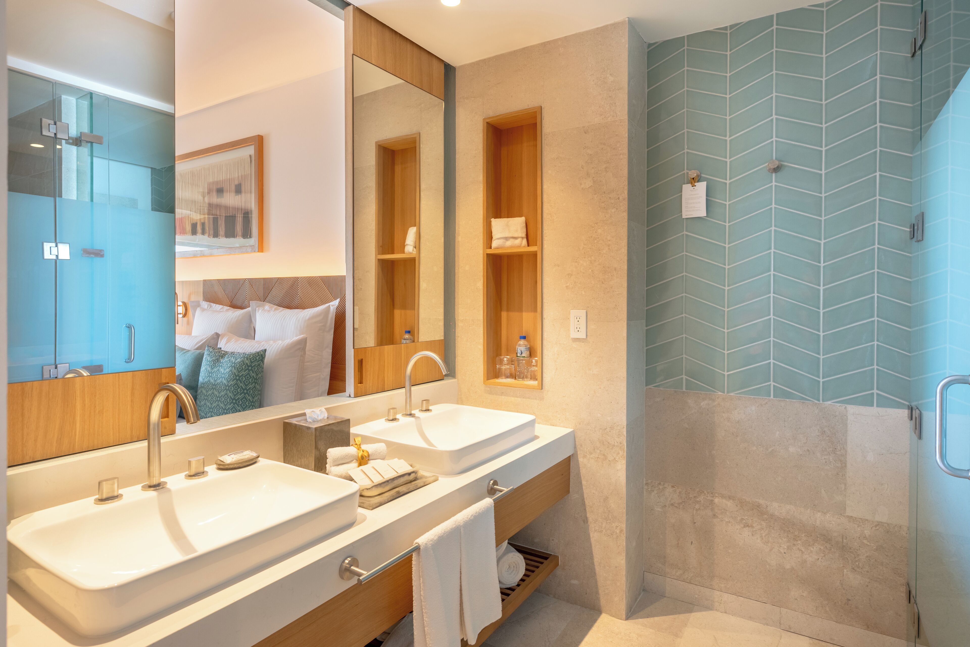 A modern bathroom with two sinks, a large mirror, and a shower area.