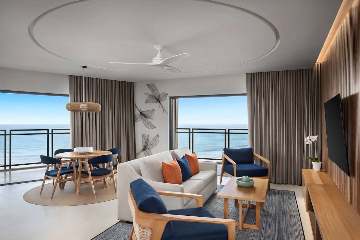 Un salon moderne comprenant un canapé, des fauteuils, une table à manger et un ventilateur de plafond.