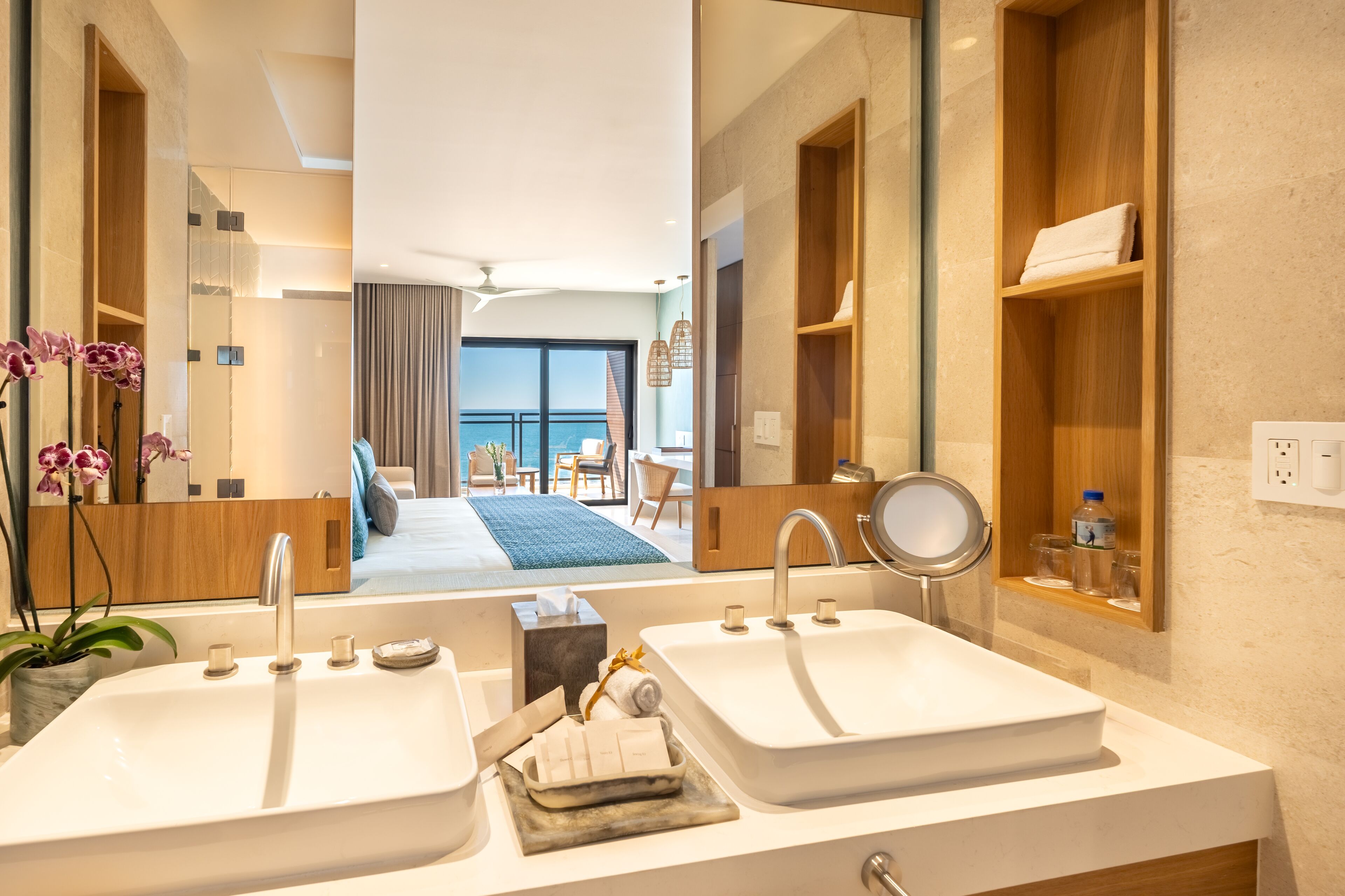 Un baño moderno con dos lavabos, un espejo grande y vistas a un balcón con sofá y sillones.