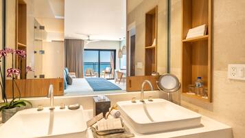 A modern bathroom with two sinks, a large mirror, and a view of a balcony with a sofa and chairs.