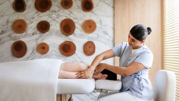 Eine Massageanwendung in einer Wellnessumgebung mit Marmorwand und Holzelementen.