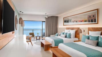 Ein modernes Hotelzimmer mit zwei Betten, einem großen Fernseher, einem Balkon mit Aussicht und einer Essecke.