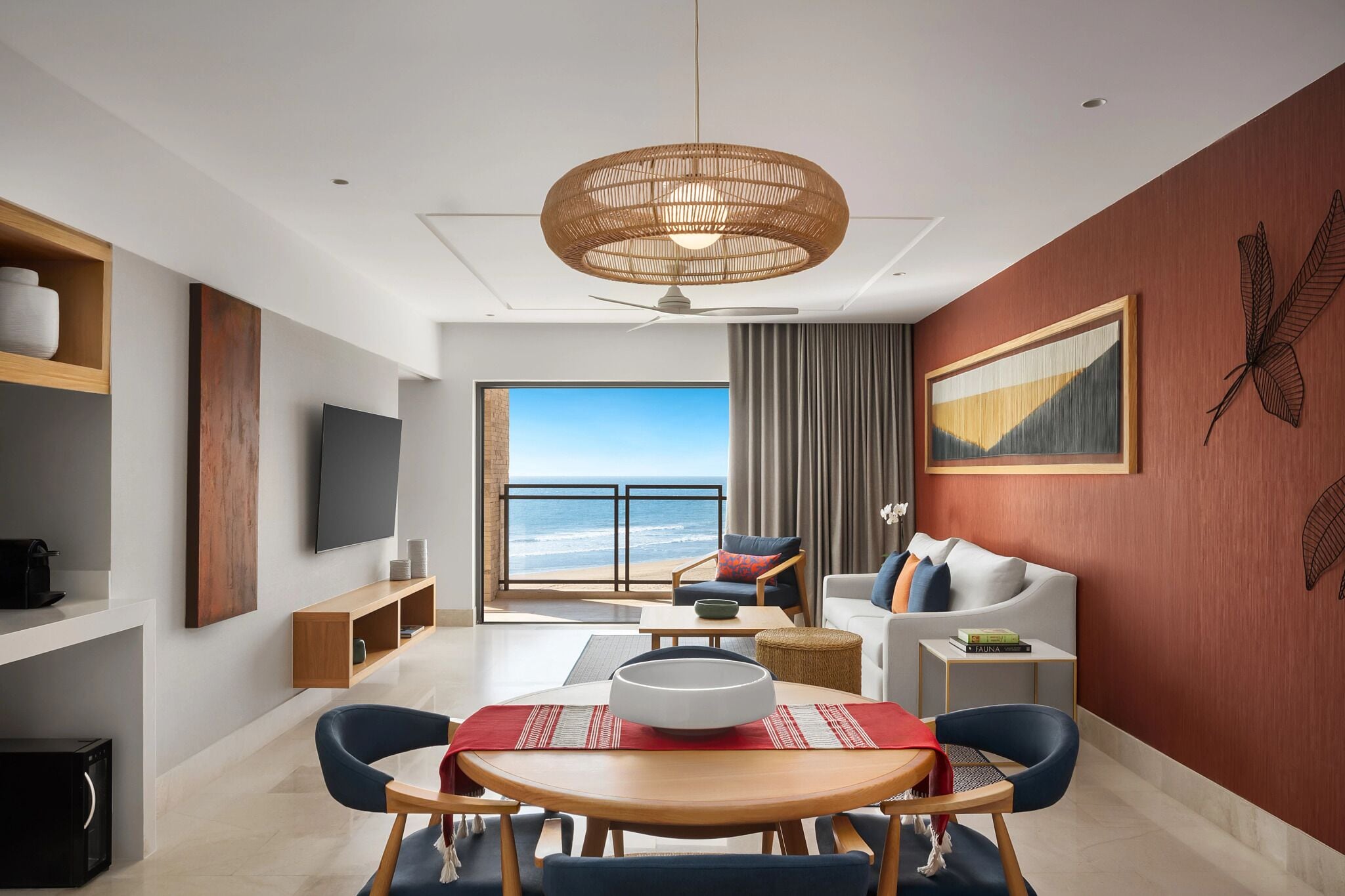A modern living room with a large window, a dining table, and a ceiling fan.