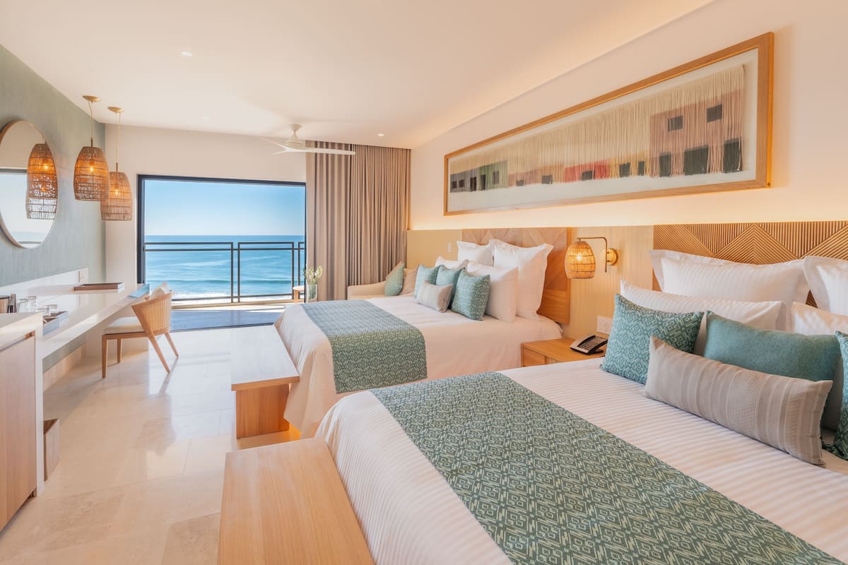 Une chambre d’hôtel avec deux lits, un bureau et une vue sur la mer.