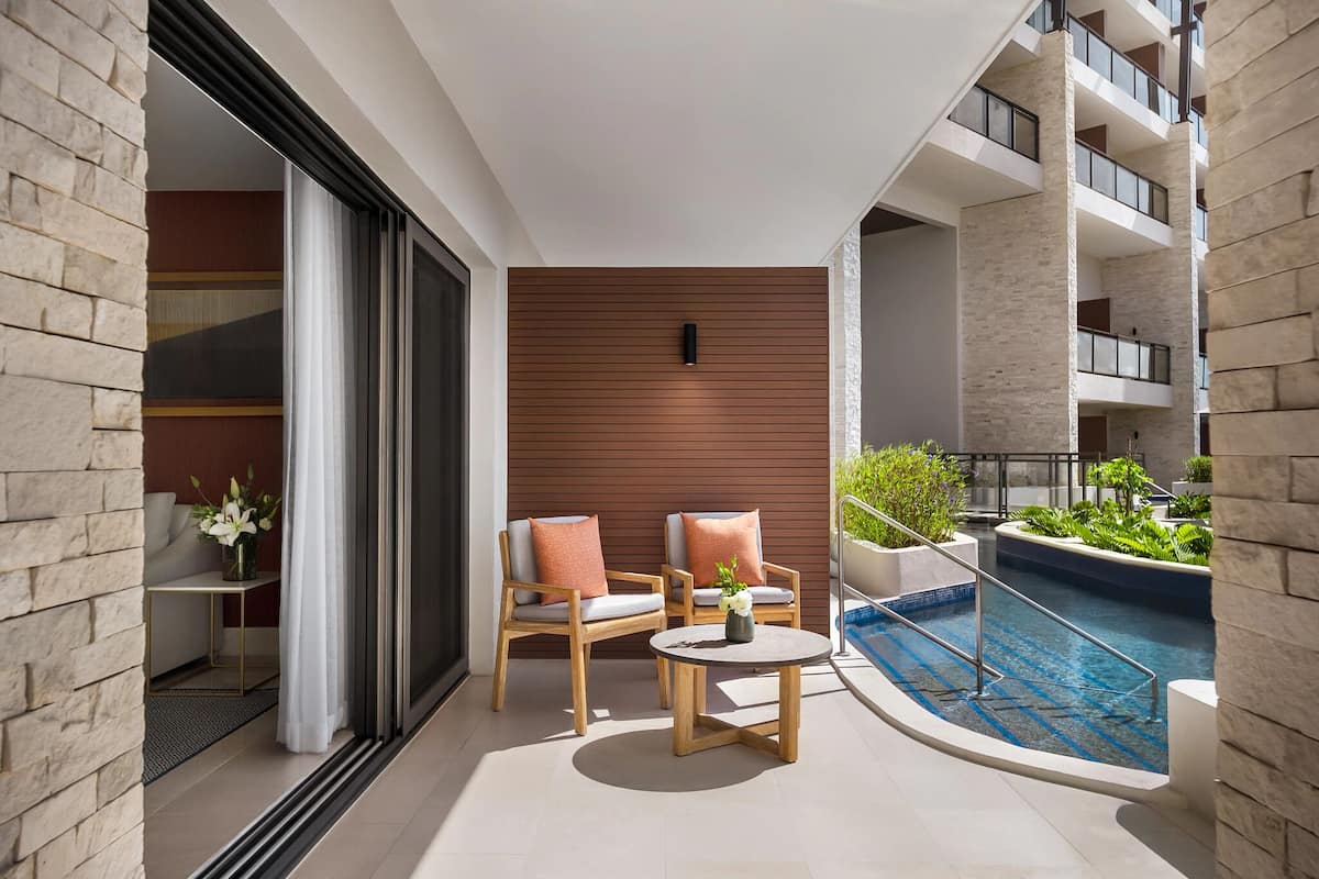 Un balcon moderne avec deux chaises en bois, une petite table ronde et une piscine.