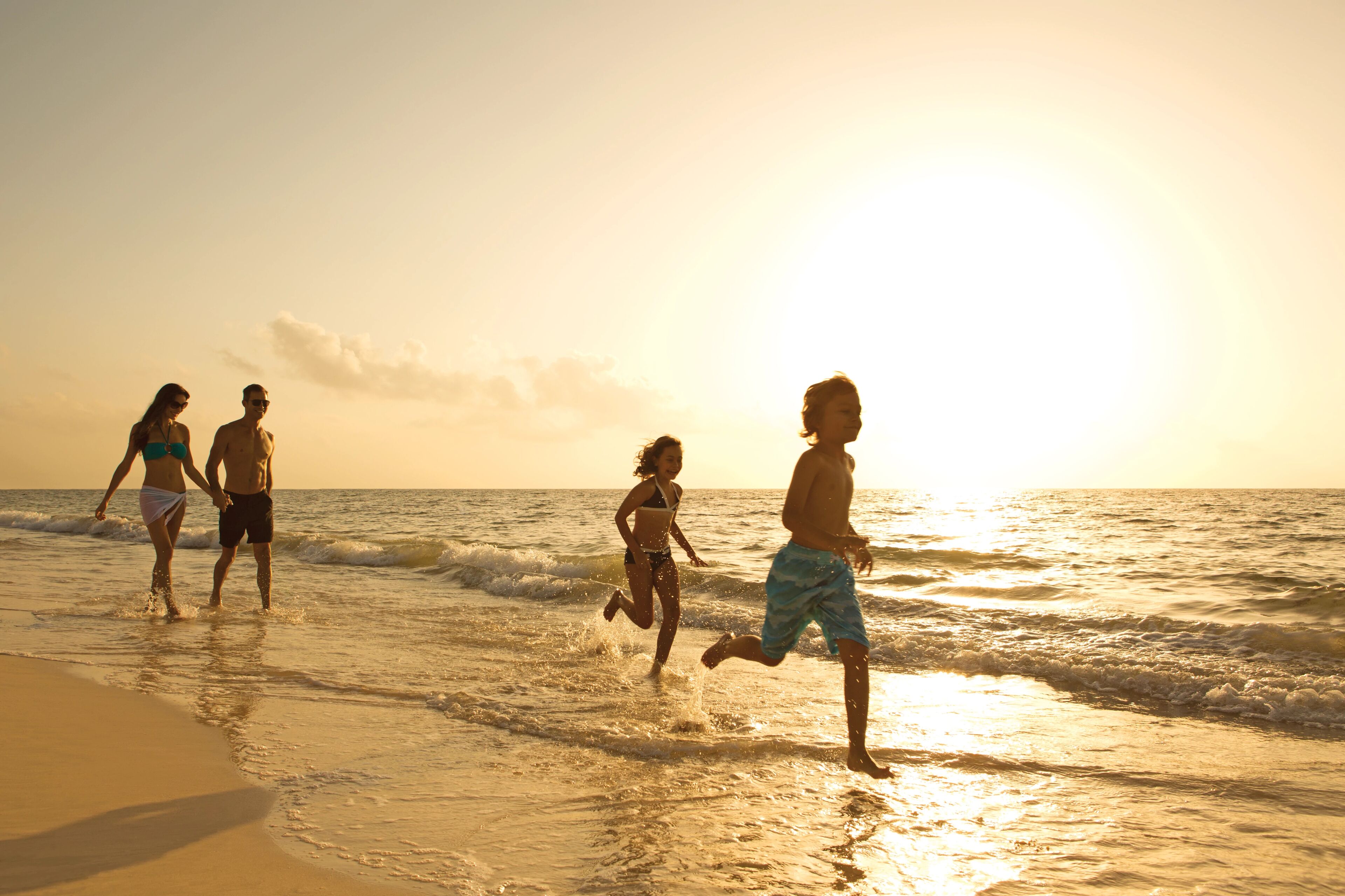 A beach scene with people running along the shore.