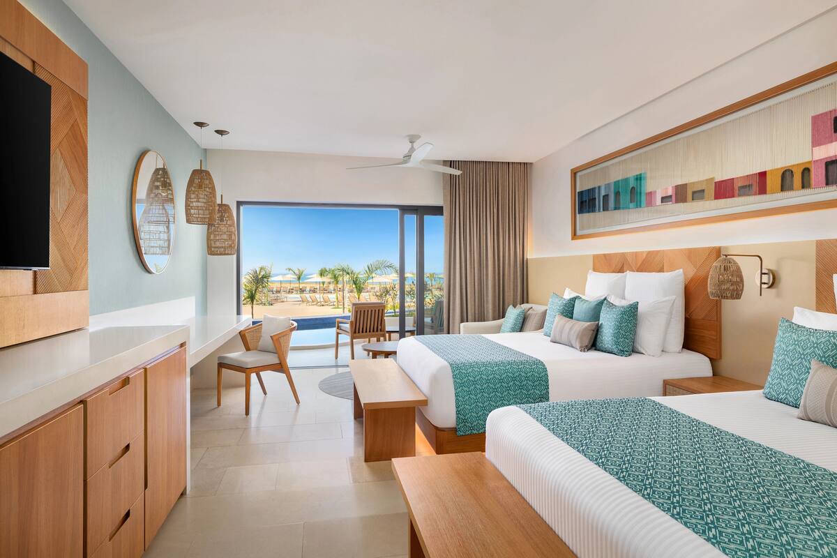 Une chambre d’hôtel avec un grand lit, un bureau, une chaise et une vue sur la plage.