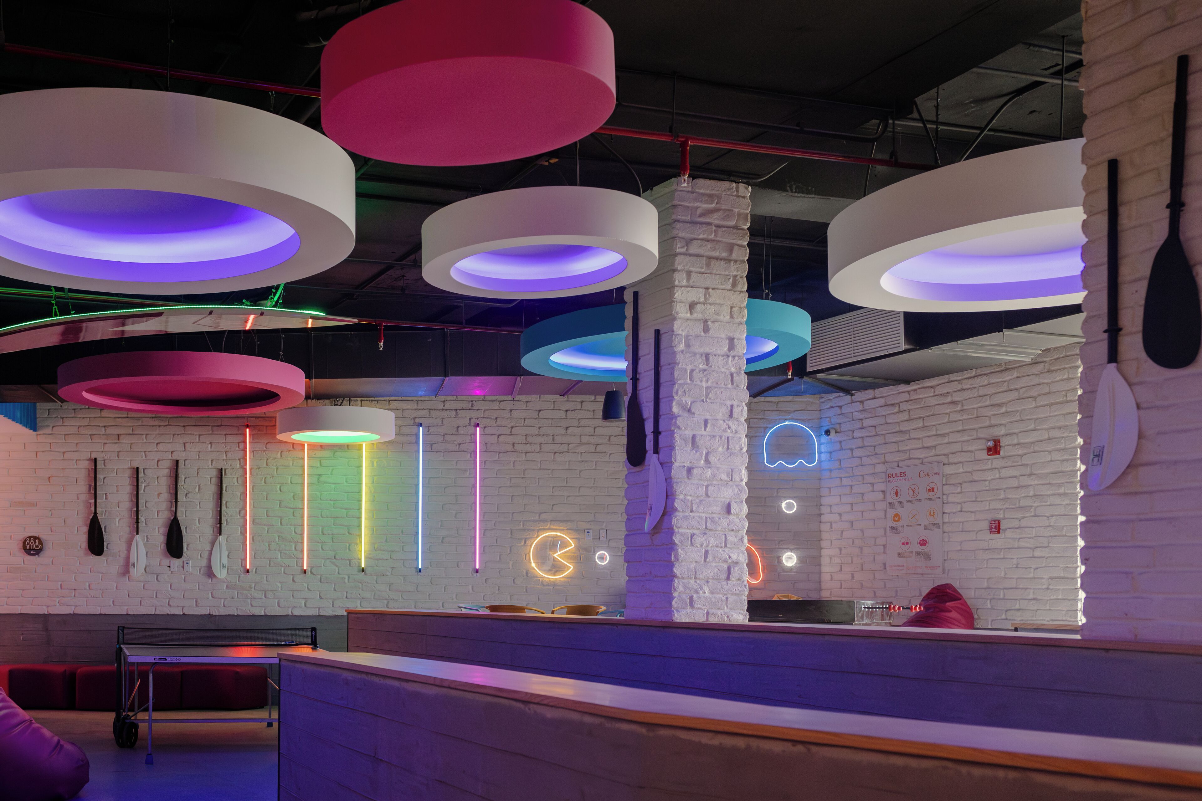 Un interior moderno con paredes de ladrillo visto, luces de neón y una zona de bar.