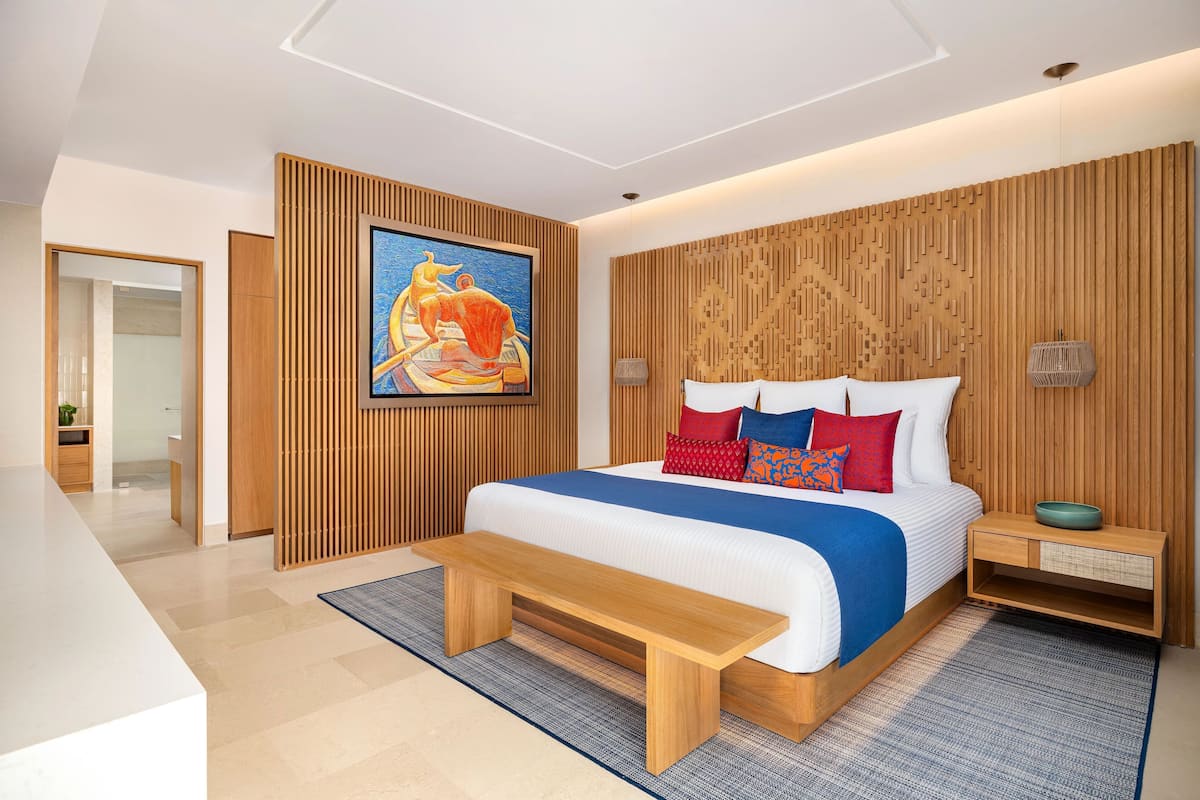 Une chambre moderne avec un grand lit, un lambris en bois, un tableau et une table de chevet sur laquelle se trouve un bol.