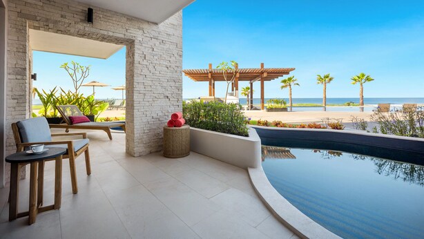 Ein moderner Außenbereich mit Pool, Liegestühlen und Blick auf den Strand.