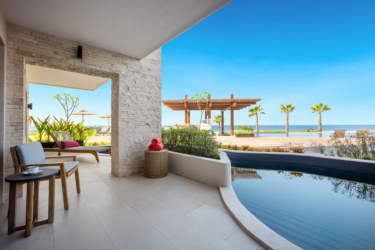 Un espace extérieur moderne doté d’une piscine, de chaises longues et offrant une vue sur la plage.