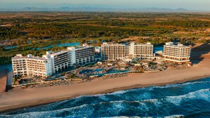 Ein Strandhotel mit mehreren Gebäuden, einem Poolbereich und direktem Zugang zum Strand.