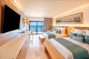 Een hotelkamer met twee bedden, een televisie, een bureau en uitzicht op de oceaan.