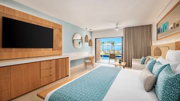 A modern hotel room with a large bed, a flat-screen TV, a balcony with a pool view, and a wooden cabinet.