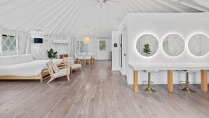 Tilava, telttamaisesti suunniteltu huone, jossa on sänky, oleskelualue ja ruokapöytä.
