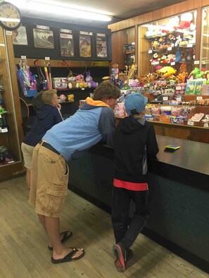 A store interior with shelves stocked with toys and merchandise, a clock on the wall, and a counter with various items for sale. - Huge Beach House with 2 car garage (Hampton)