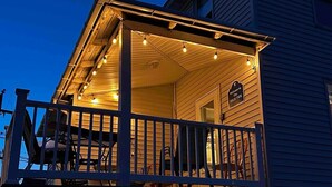 Une terrasse en bois avec une rambarde, des guirlandes lumineuses et un panneau indiquant la hauteur maximale de la marée.