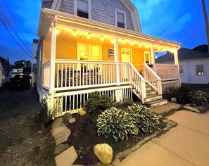 A two-story house with a porch, a staircase, and a sign that reads "Lazy Parrot." - Beautiful 4 bedroom, 1.5 bath Beach Cottage with Central AC (Hampton)