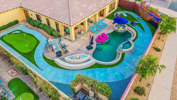 A residential property with a swimming pool, outdoor seating, and a well-maintained lawn.