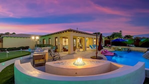 A pool area with a hot tub, lounge chairs, and a covered seating area.