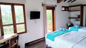 Ett rum med en säng, ett skrivbord, en stol, en tv och en balkong med ett träräcke.