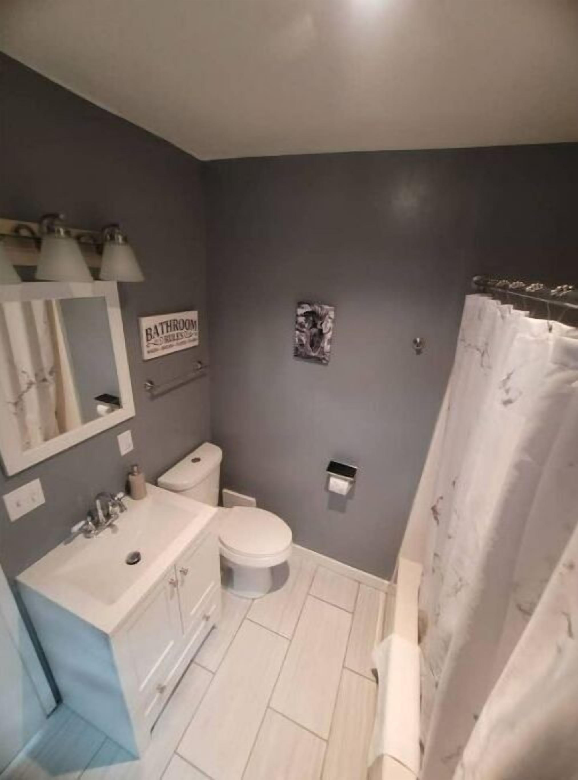 Et badeværelse med toilet, vask og bruseforhæng.