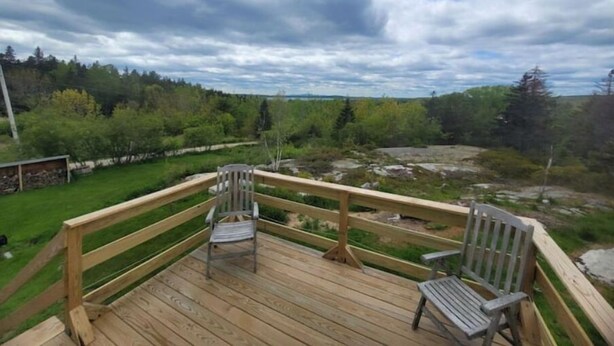 A wooden deck with two chairs and a view of a forested landscape. - 3BR House Plus Bonus 1BR Apt at The Rockbound House 1Hr to Acadia National Park (Brooklin)