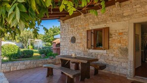 Un bâtiment en pierre avec une table et des bancs en bois, un jeu de fléchettes et une fenêtre avec des volets en bois.