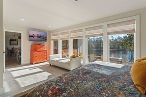 A spacious living room with a large window, a sofa, a coffee table, and a television.