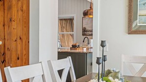 A dining area with a wooden table, white chairs, and a vase with flowers.