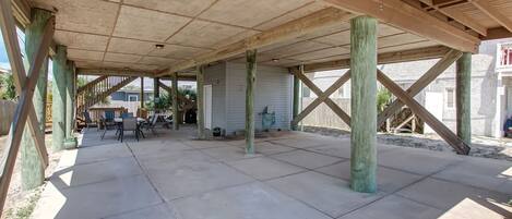 An open patio with a wooden deck, concrete flooring, and a view of a house in the background.