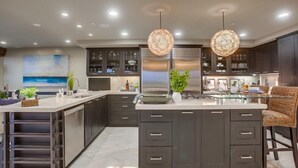 Una cocina moderna con muebles oscuros, una isla central e iluminación colgante.