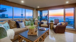 Amplia sala de estar con un gran ventanal con vista al océano, amueblada con un sofá, sillones y una mesa de centro.