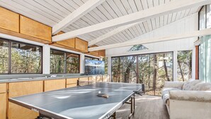 A ping pong table in a room with large windows, wooden cabinets, and a sofa. - River Retreat RV Campground ~ Gym / Game Room / Sauna (Jacksonville)