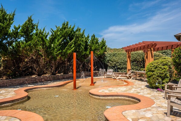 A landscaped outdoor area with a water feature, seating, and a pergola.