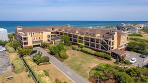 Un edificio residencial de varios pisos con un patio central, rodeado de céspedes y árboles bien cuidados.